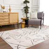 Living room scene with Azzan Cream & Charcoal Area Rug, wood cabinet, gray chair, and Southwestern style decor. Roomscene-Rectangle