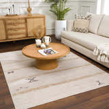 Living room scene with a Deja Cream & Gold Area Rug, wood furniture, and neutral decor. Modern bohemian style. Roomscene-Rectangle