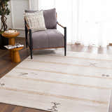 Living room scene with a Deja Cream & Gold Area Rug. The rug has a subtle trellis pattern and complements the gray chair. Roomscene-Rectangle