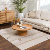 Living room scene with a Deja Cream & Gold Area Rug, light sofa, wood coffee table, and natural decor creating a cozy, bohemian vibe. Roomscene-Rectangle