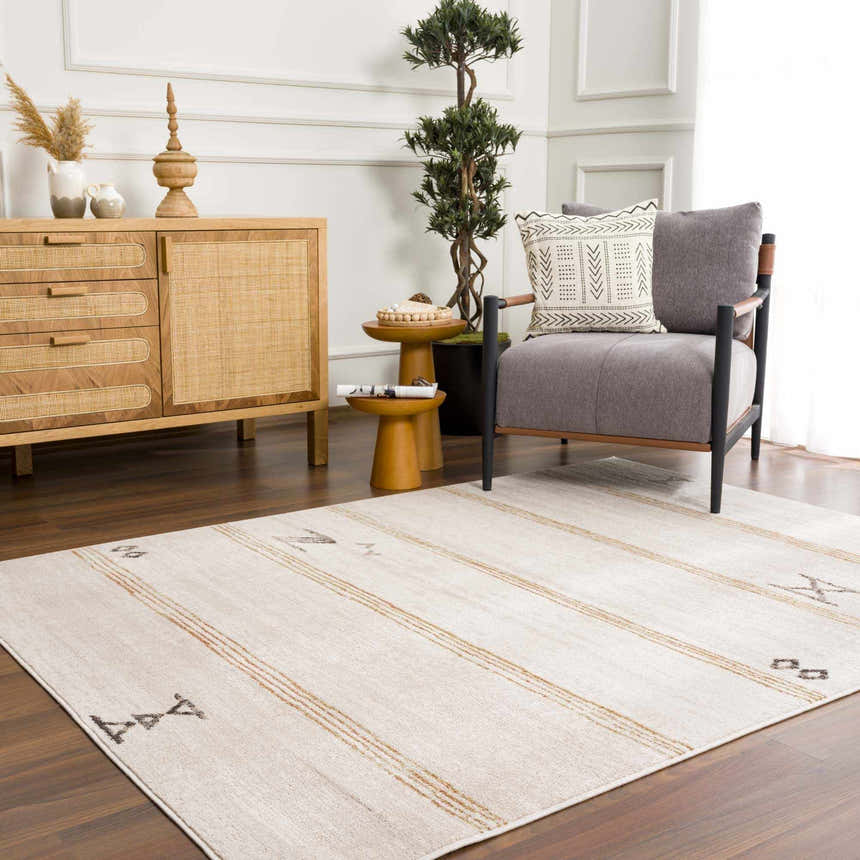 Living room scene with Deja Cream & Gold Area Rug, wood furniture, gray chair, and potted tree. Bohemian style. Roomscene-Rectangle