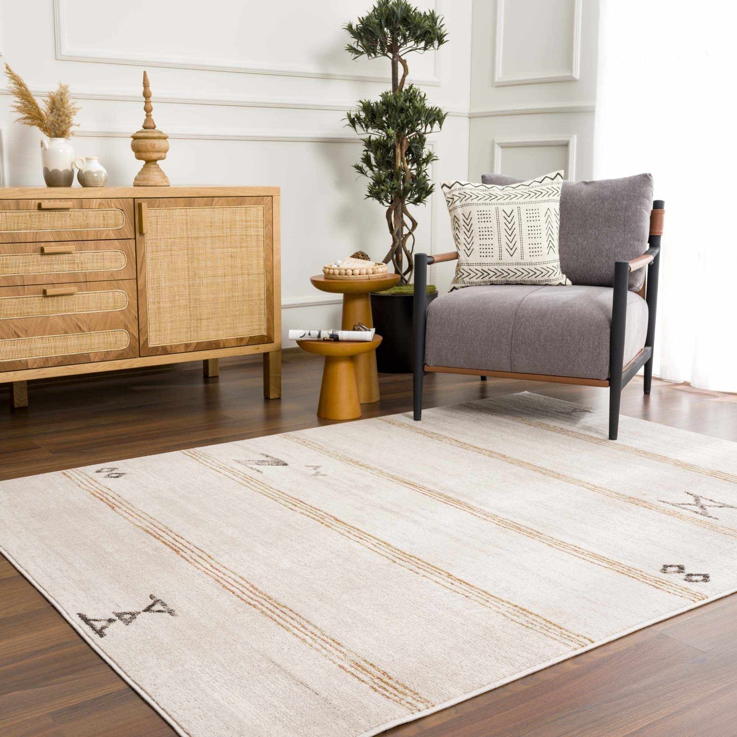 Living room scene with Deja Cream & Gold Area Rug, wood furniture, gray chair, and potted tree. Bohemian style. Roomscene-Rectangle