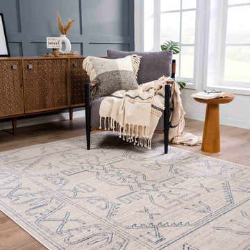Living room scene with a Divya Cream & Silver Blue Area Rug, gray chair, wood cabinet, and warm, inviting decor. Roomscene-Rectangle