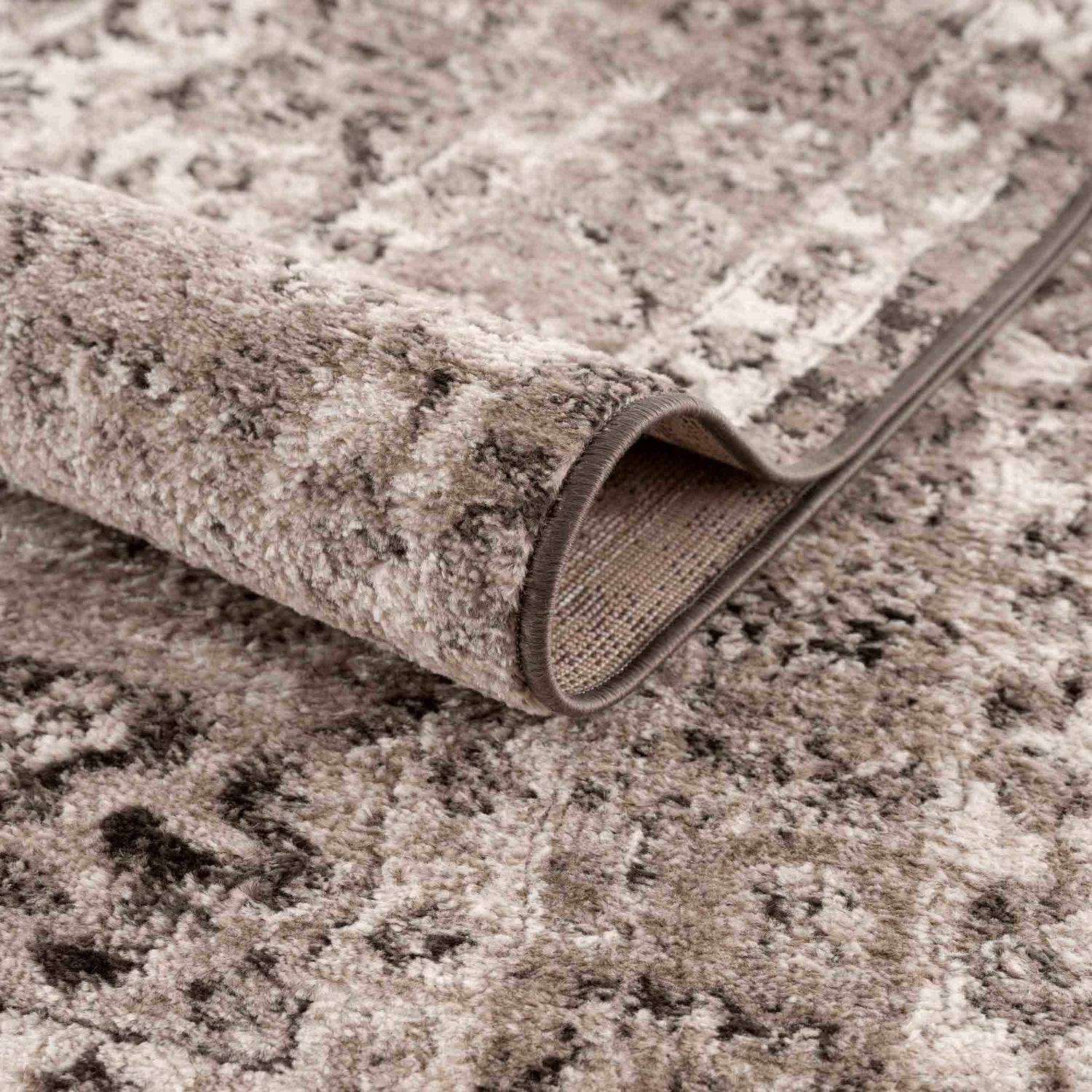 Close-up of the Albie Charcoal & Beige Area Rug showing its abstract pattern and soft, textured pile. Fold