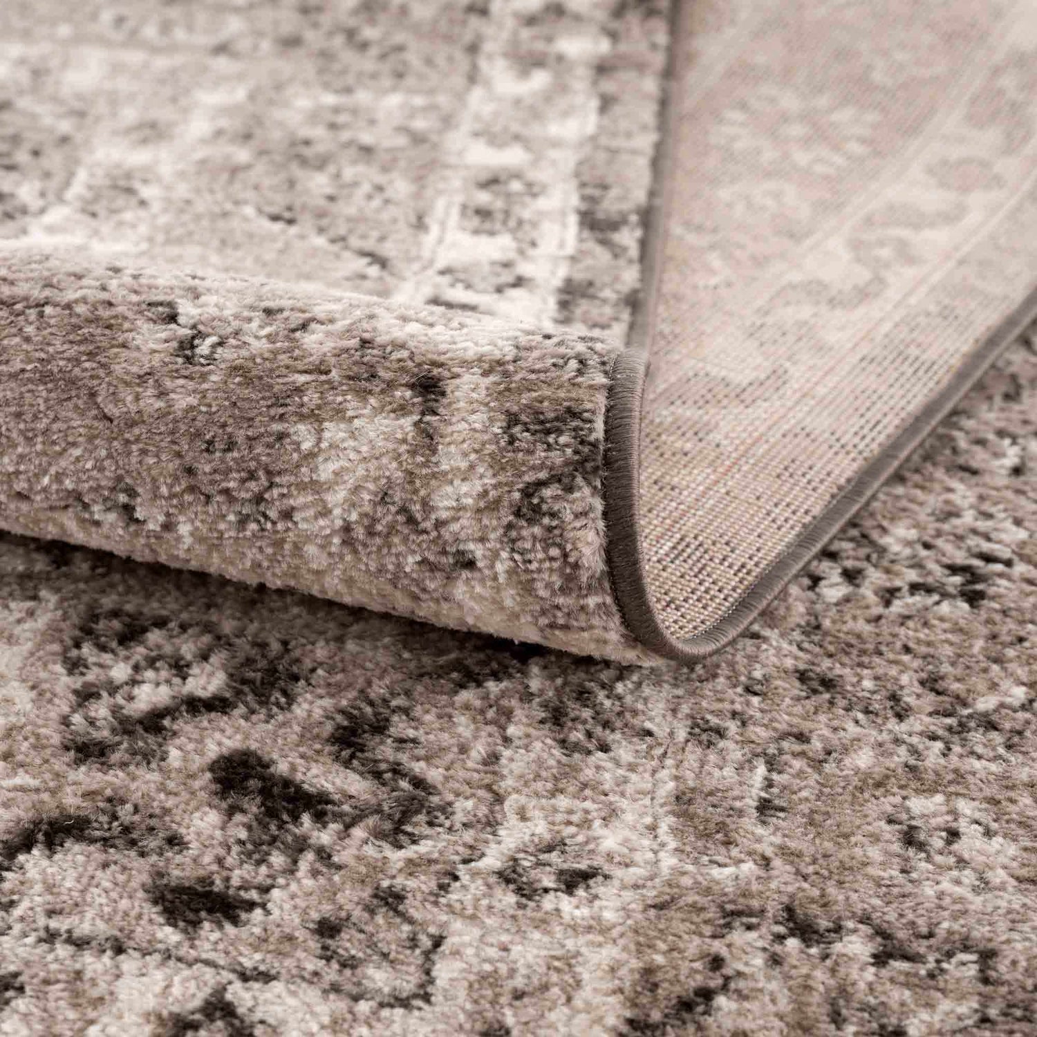 Close up of the Albie Charcoal & Beige Area Rug showing its plush texture, neutral colors, and woven backing. Fold