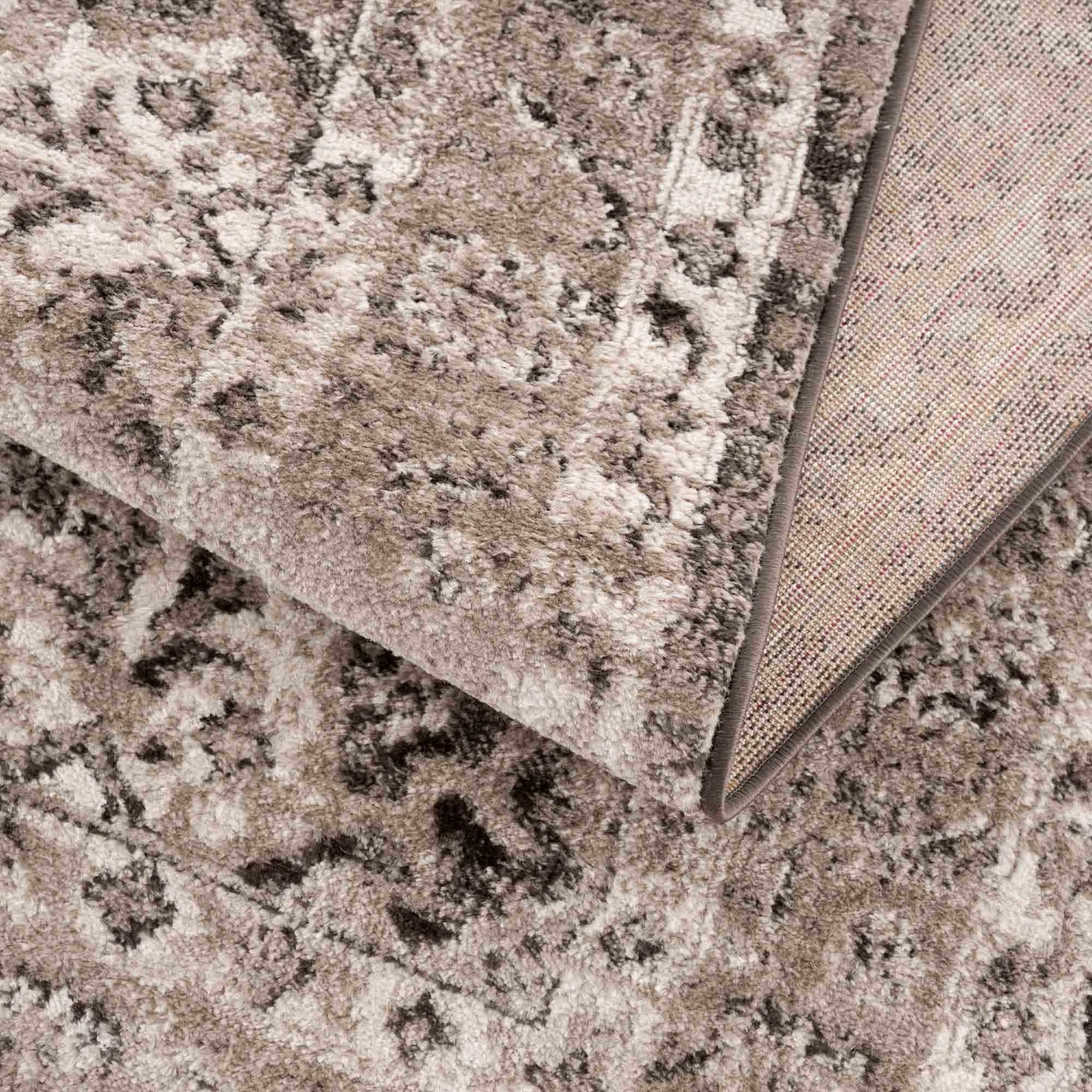 Close-up of the Albie Charcoal & Beige Area Rug showing its traditional pattern, soft texture, and woven backing. Fold