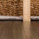 Close-up of the Albie Charcoal & Beige Area Rug pile height, measured with a ruler next to a woven basket. Pile