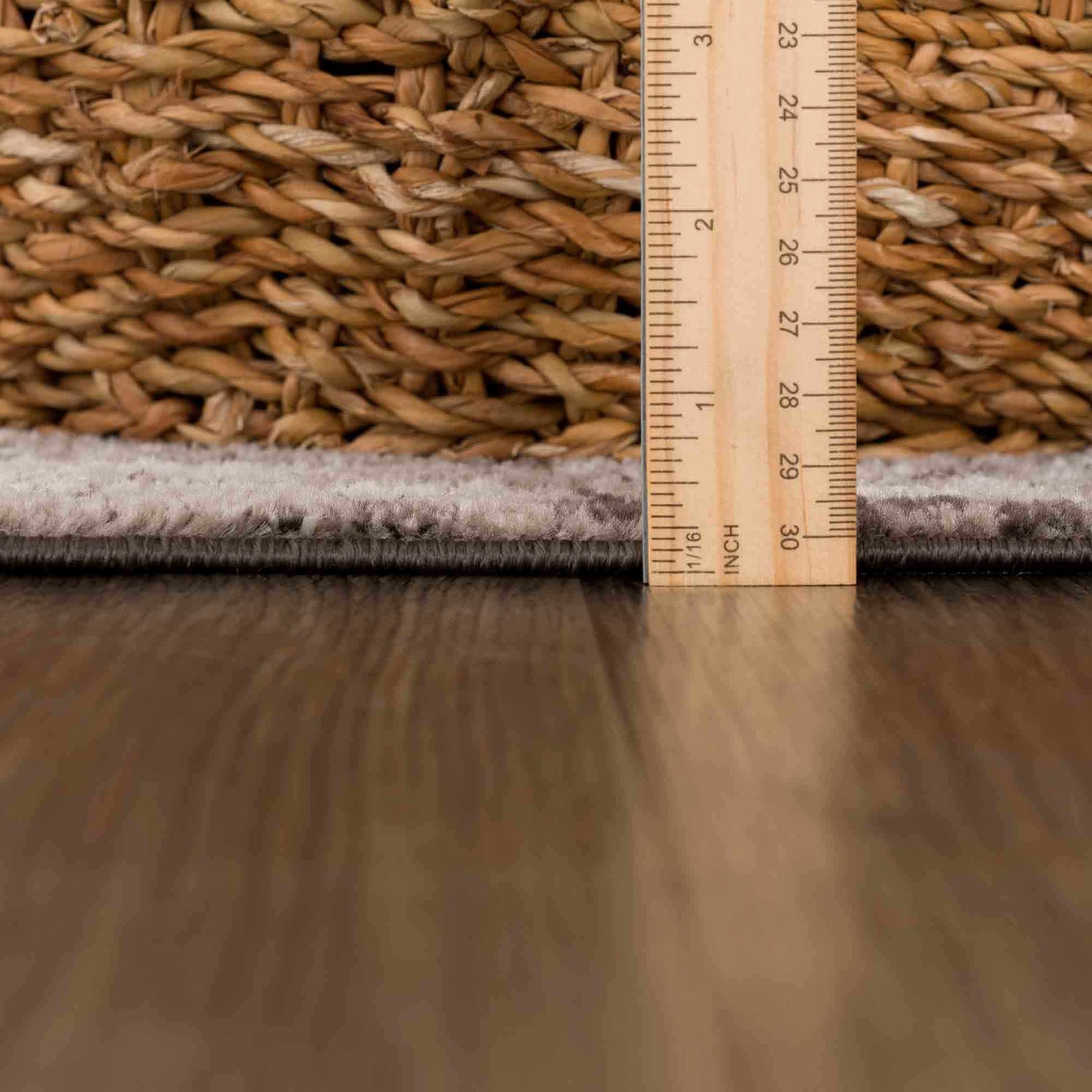 Close-up of the Albie Charcoal & Beige Area Rug pile height, measured with a ruler next to a woven basket. Pile