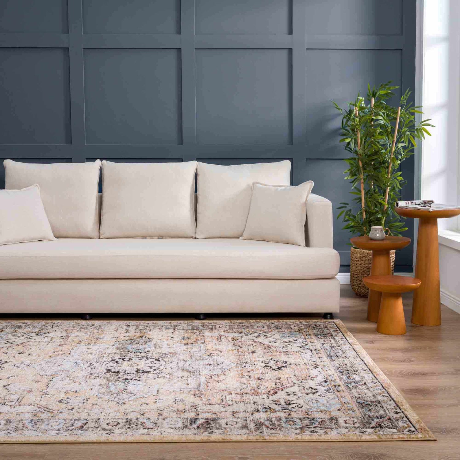 Living room scene with Albie Gold & Beige Area Rug, cream sofa, blue accent wall, and wood side tables. Roomscene-Rectangle