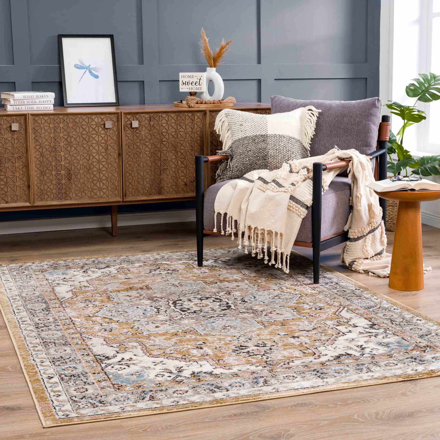Living room scene with Albie Gold & Beige Area Rug, wood cabinet, gray chair, and neutral accents. Vintage style. Roomscene-Rectangle