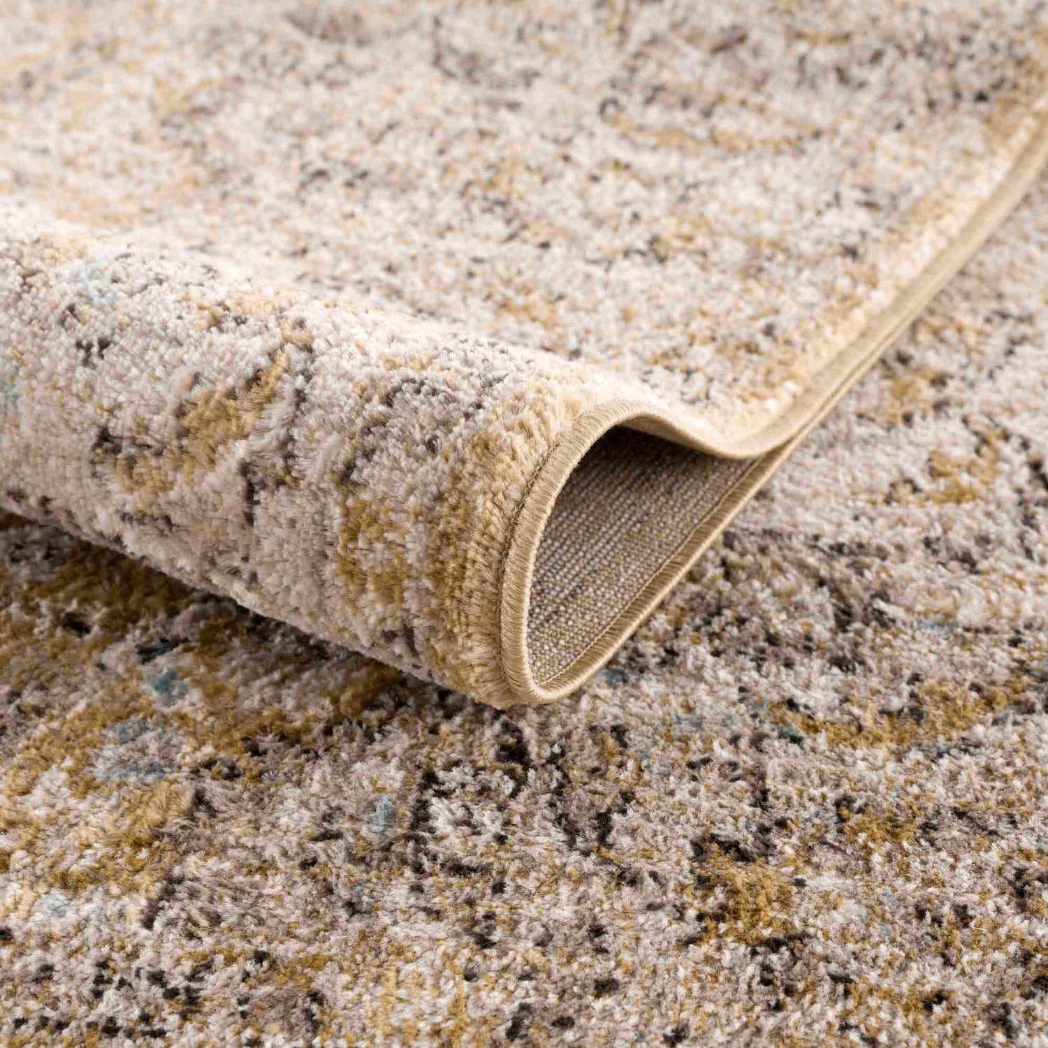Close-up of the Anana Gold & Beige Area Rug showing its texture, backing, and traditional pattern. Fold