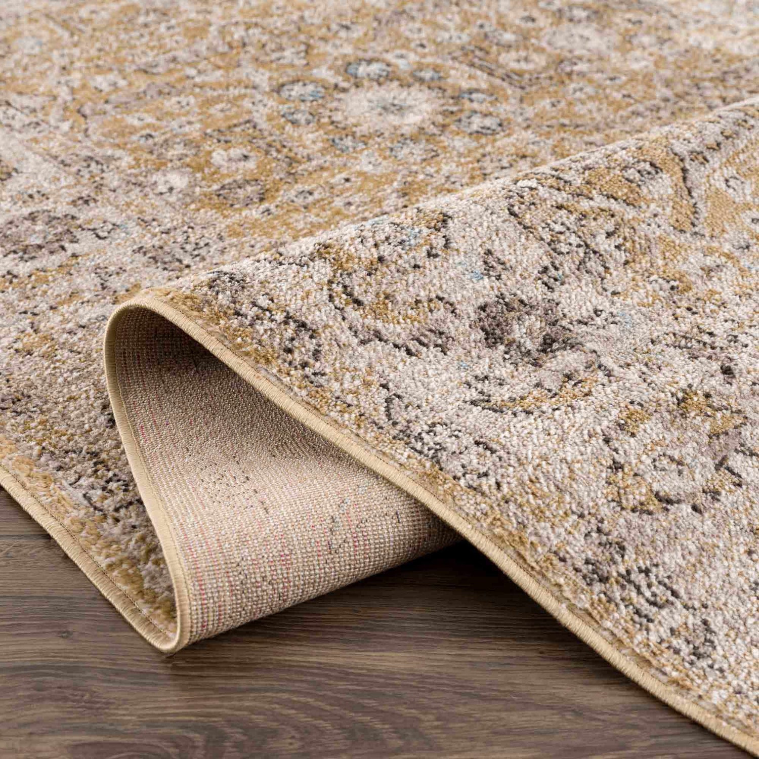 Close-up of the Anana Gold & Beige Area Rug showing its traditional design, gold and light beige colors, and soft, textured pile. Fold