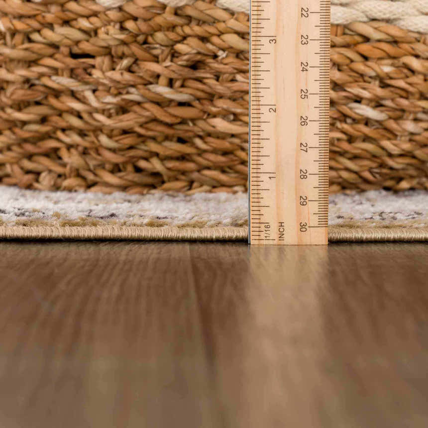 Close-up of the Anana Gold & Beige Area Rug showing the pile height with a ruler on a wood floor. Pile