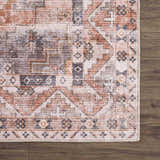Close up of Isugod Washable Area Rug. Beige, brick red, and gray oriental rug with traditional southwestern pattern on wood floor. Swatch