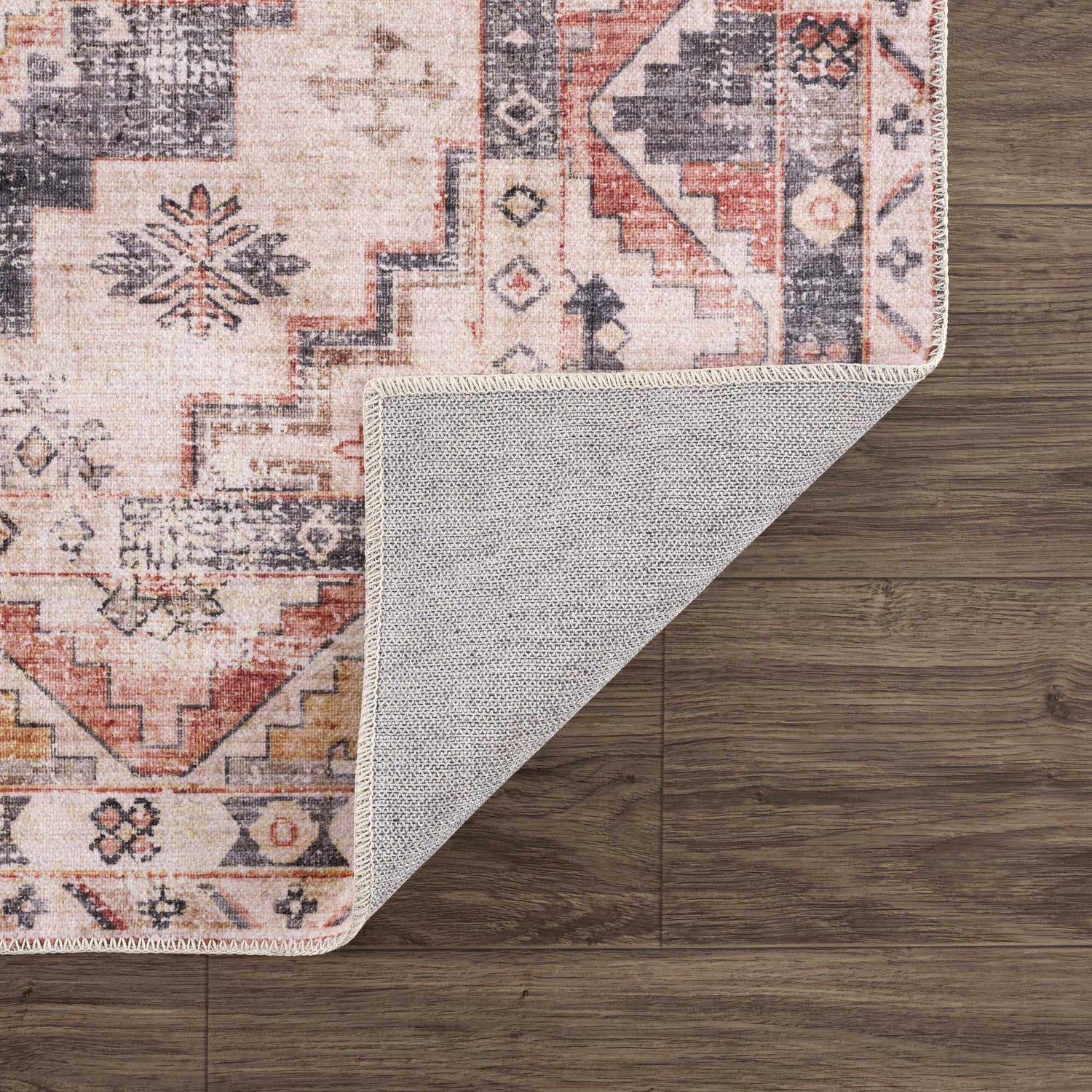 Close-up of the Isugod Washable Area Rug showing its beige, black, and brick red traditional Southwestern pattern and non-slip backing. Fold