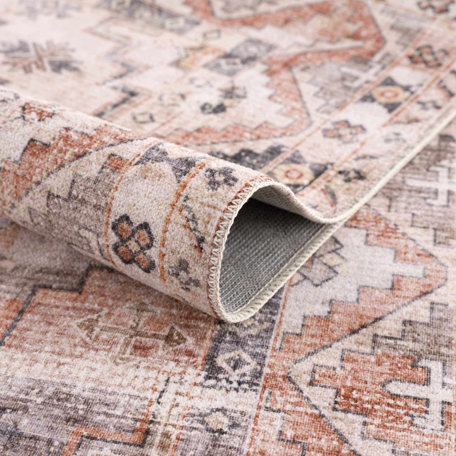 Close-up of the Isugod Washable Area Rug showing the traditional beige, brick red, and gray oriental pattern. Fold