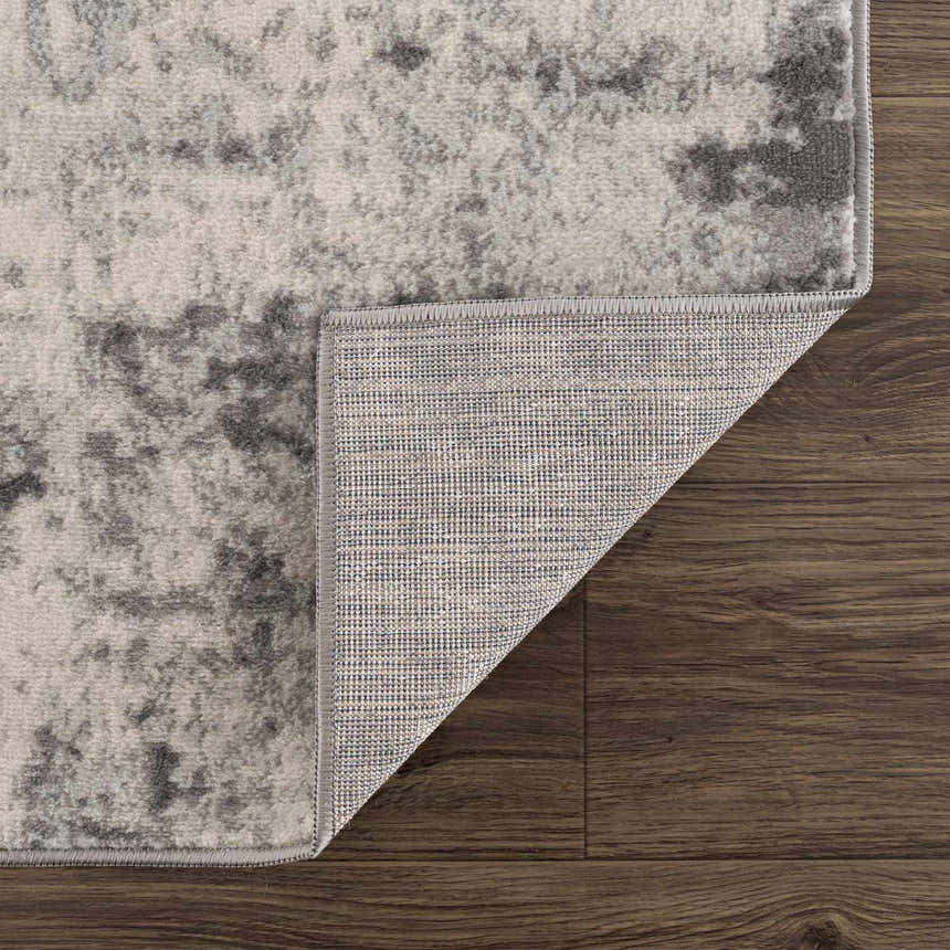 Close-up of the Kalanganan Abstract Gray Rug showing its charcoal, gray, and off-white pattern and woven backing. Fold
