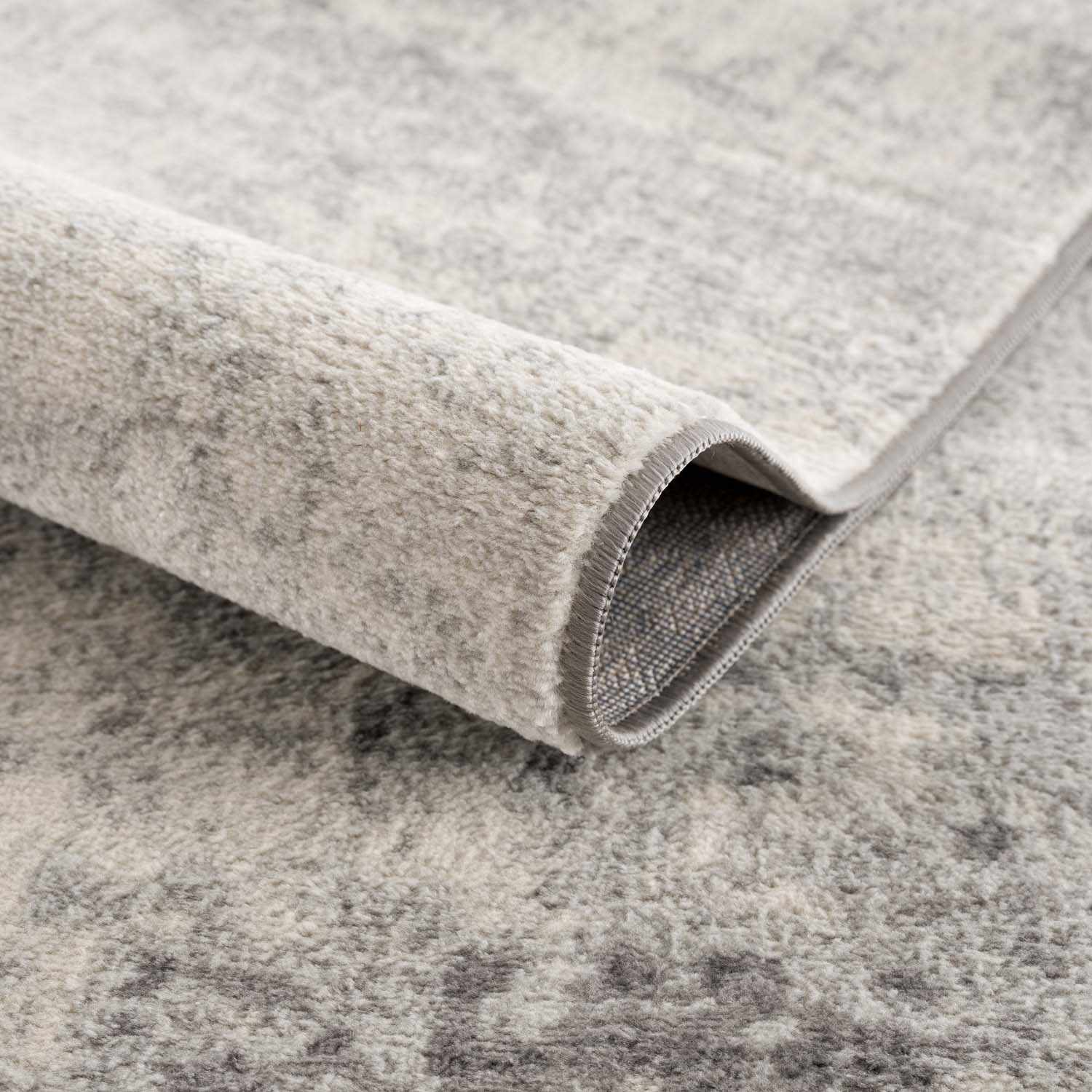 Close-up of the Kalanganan Abstract Gray Rug showing its charcoal, gray, and off-white abstract pattern and soft texture. Fold