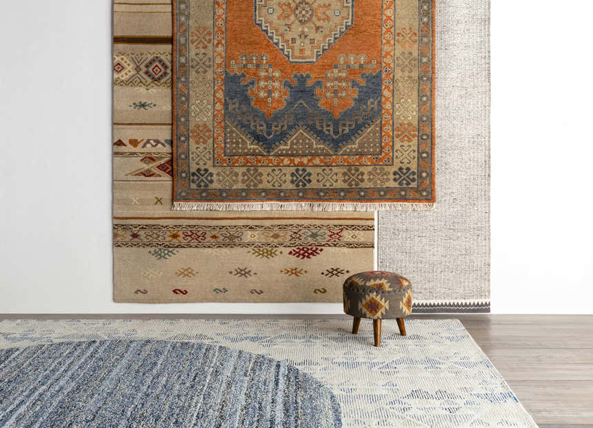 Stacked rugs featuring the Charmhaven Area Rug. Colors include blue, brown, burnt orange, and tan. Styleshot