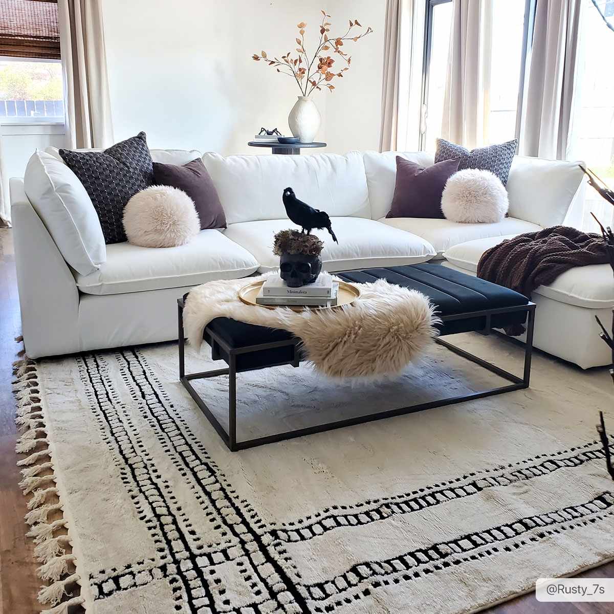 Living room scene with a white sofa and Ryuu Black & White Area Rug featuring a geometric design and fringe. Roomscene-Rectangle