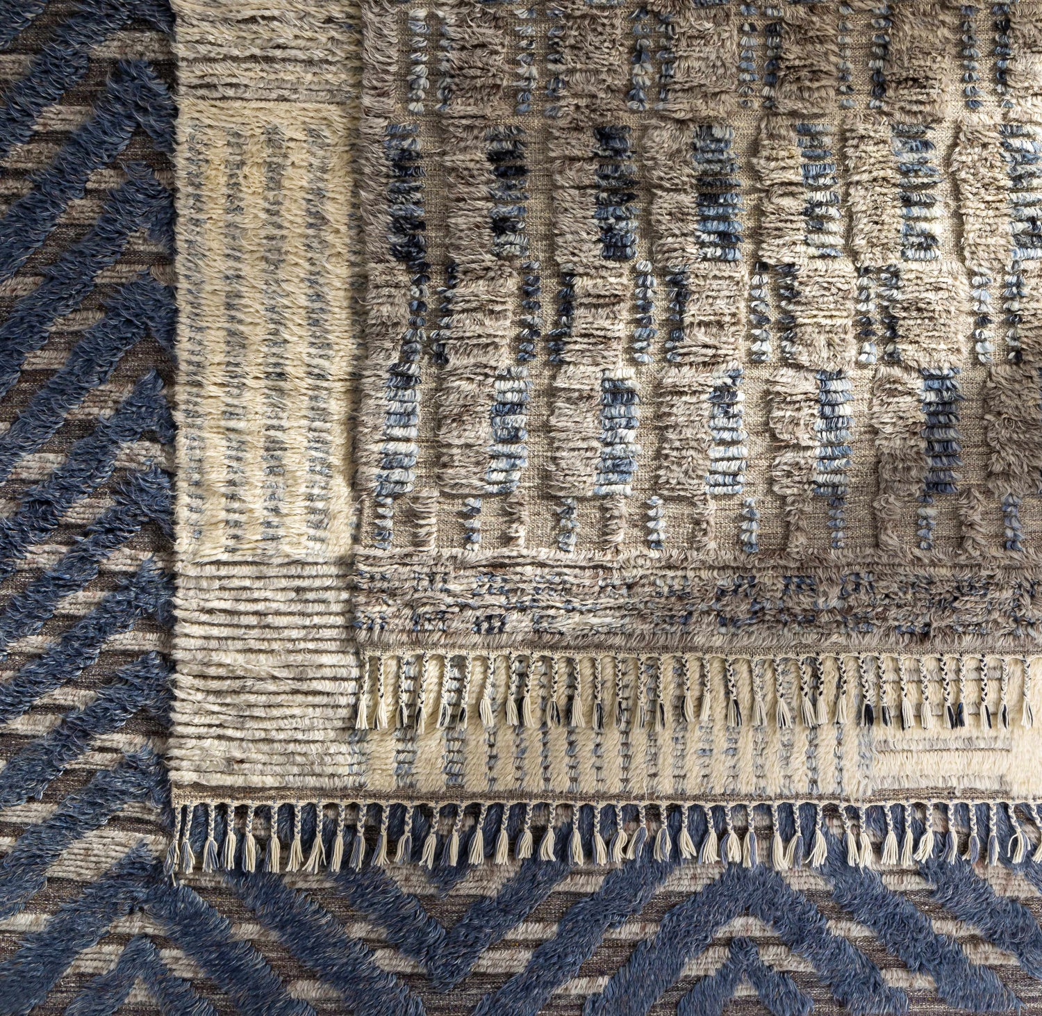 Close-up of the hand-knotted Plean Premium Rug. Features charcoal, cream, and denim hues with a textured, bohemian design. Styleshot