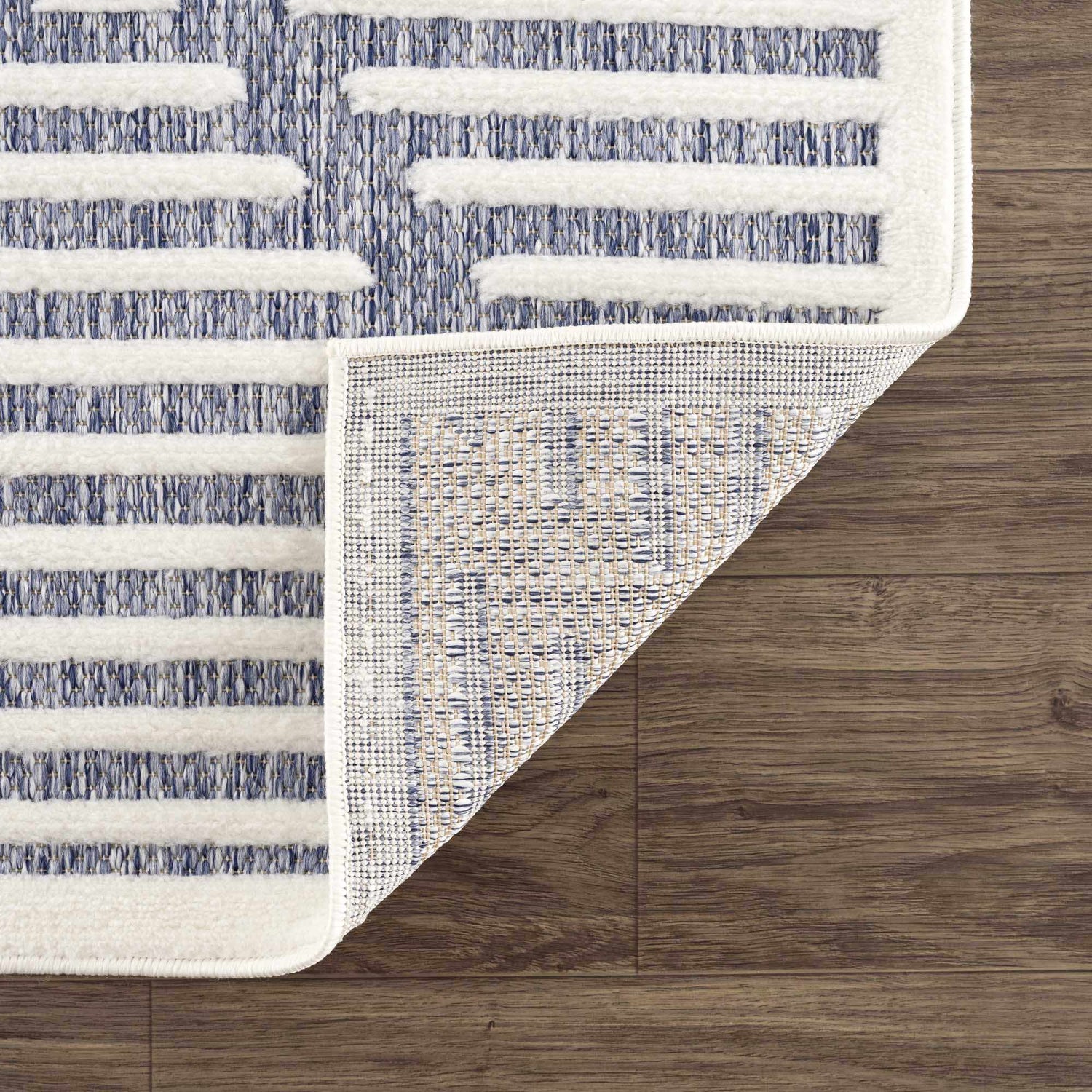 Close-up of Anah Blue Outdoor Rug showing the blue and off-white stripe design and the rug's construction. Fold