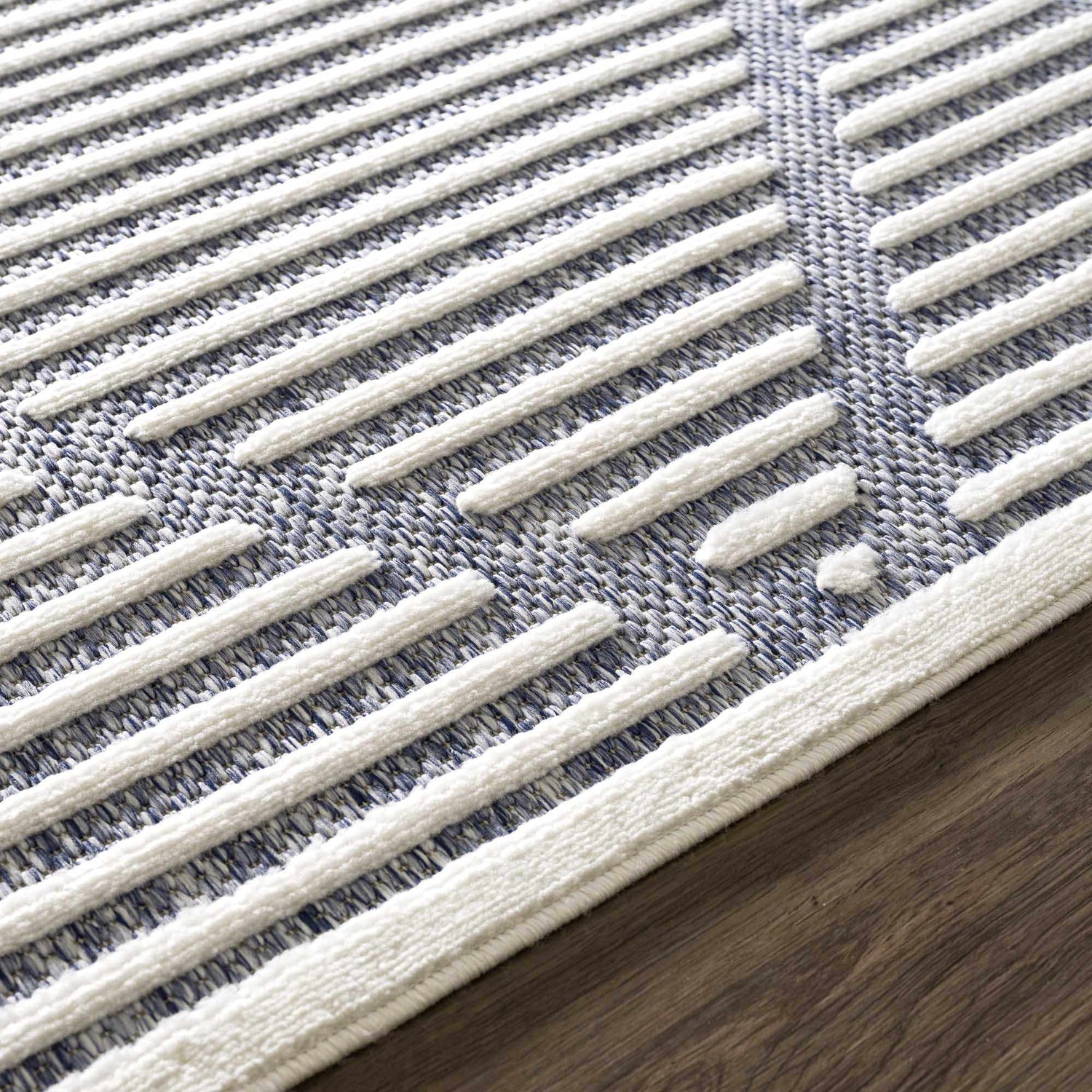 Close up of the Anah Blue Outdoor Rug showing the textured white stripes and blue woven background. Styleshot