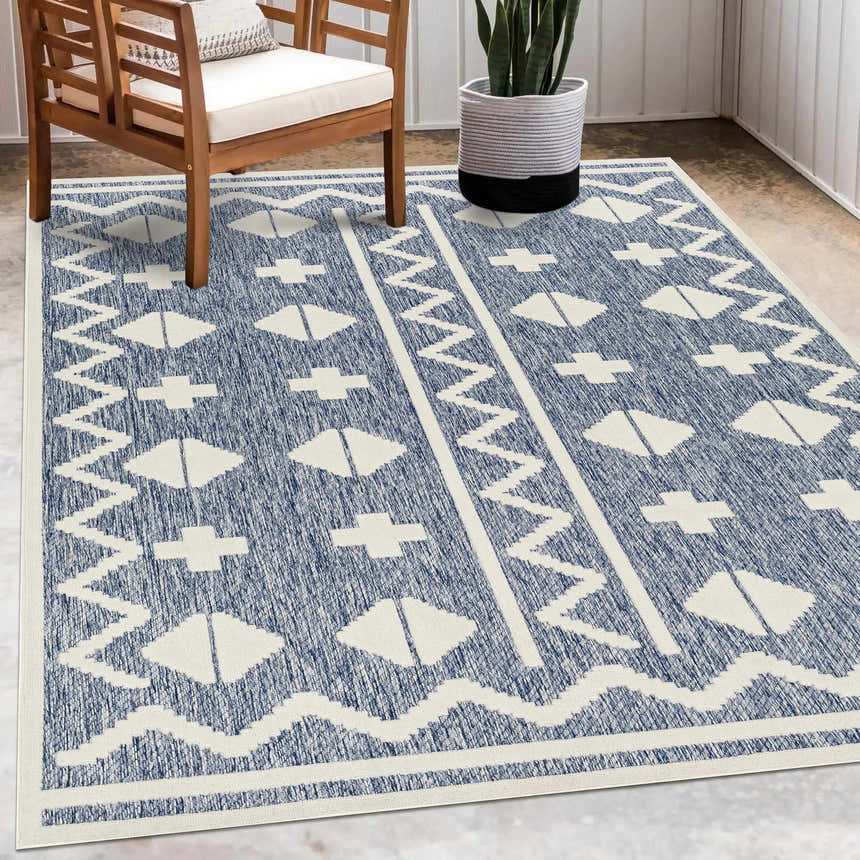 Patio scene with the Elio Blue Outdoor Rug, wooden chair, and potted snake plant. Roomscene-Rectangle