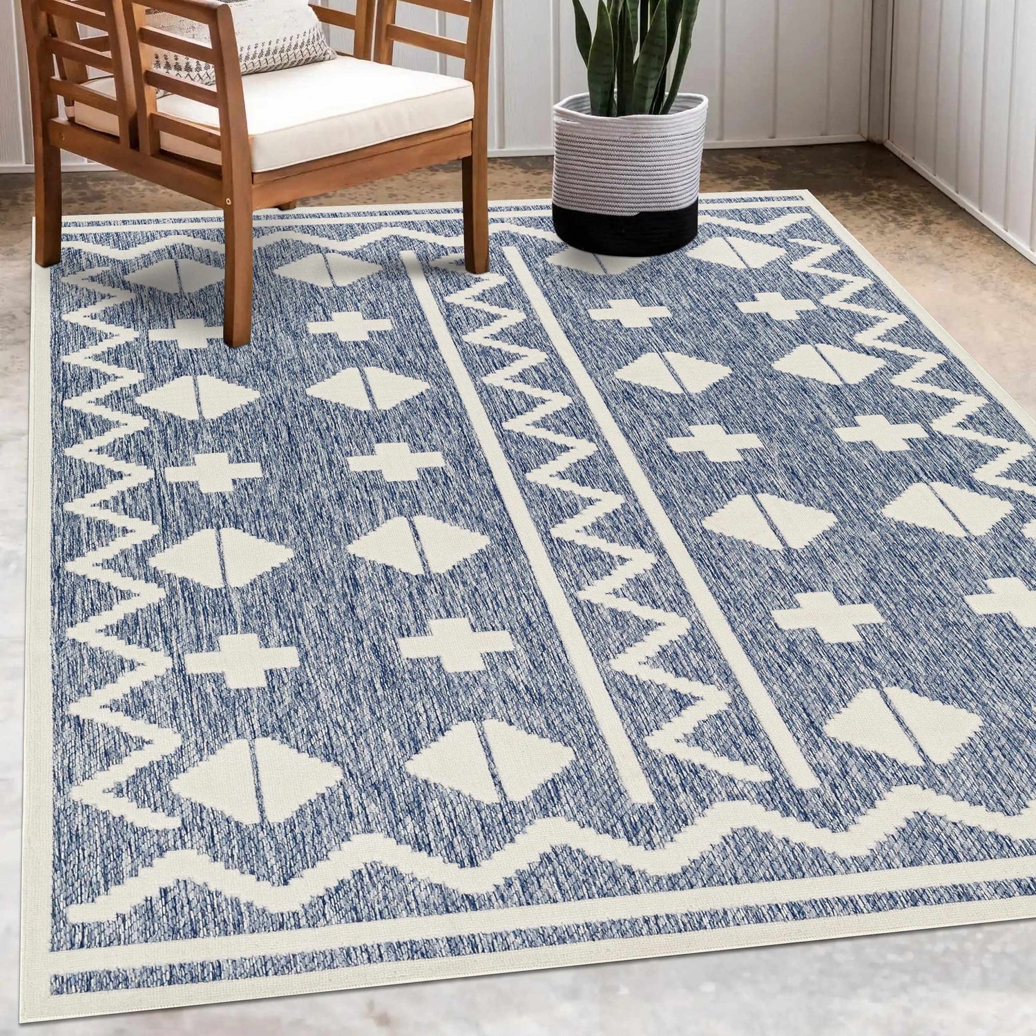 Patio scene with the Elio Blue Outdoor Rug, wooden chair, and potted snake plant. Roomscene-Rectangle