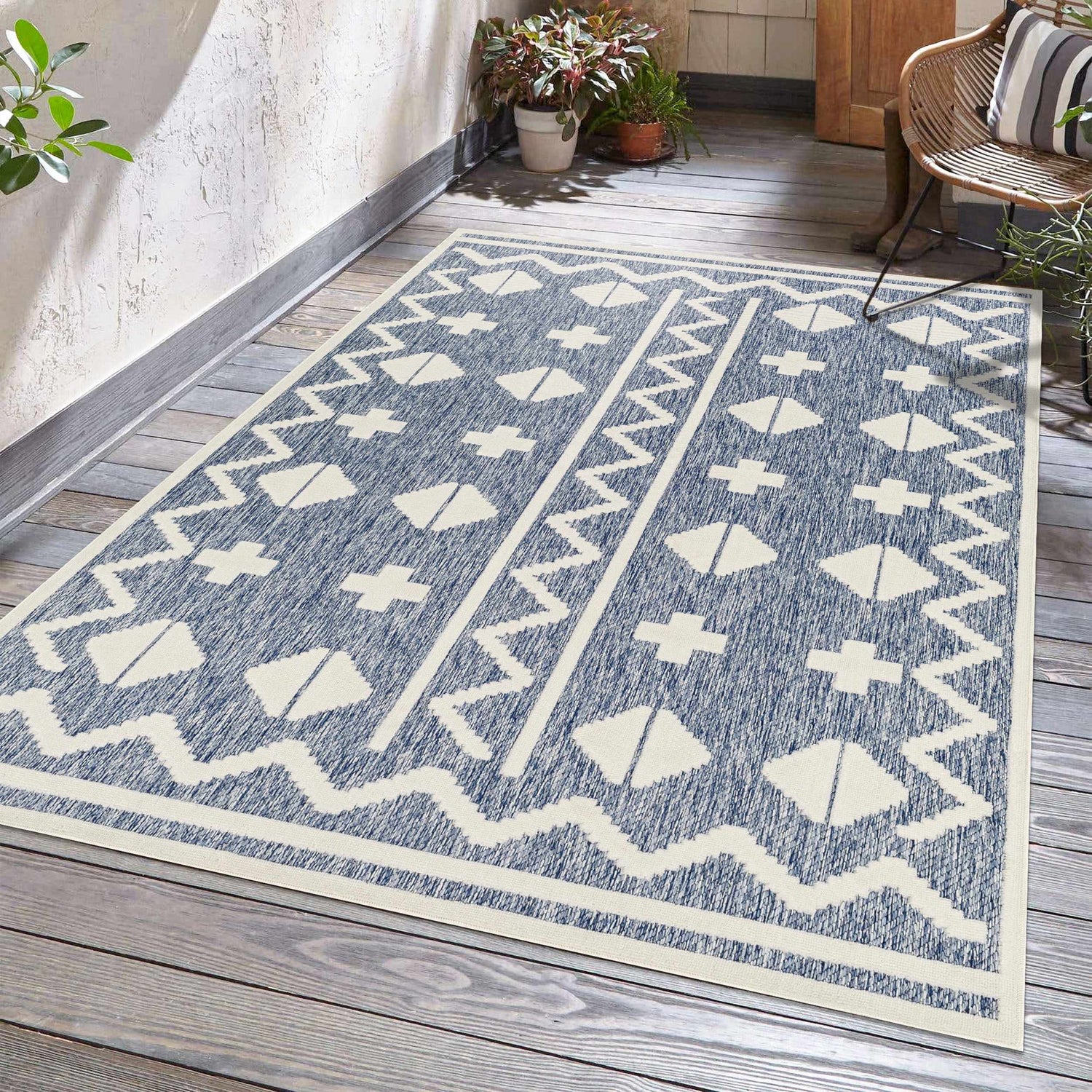 Outdoor patio scene with Elio Blue Outdoor Rug, wicker chair, and potted plants. Roomscene-Rectangle