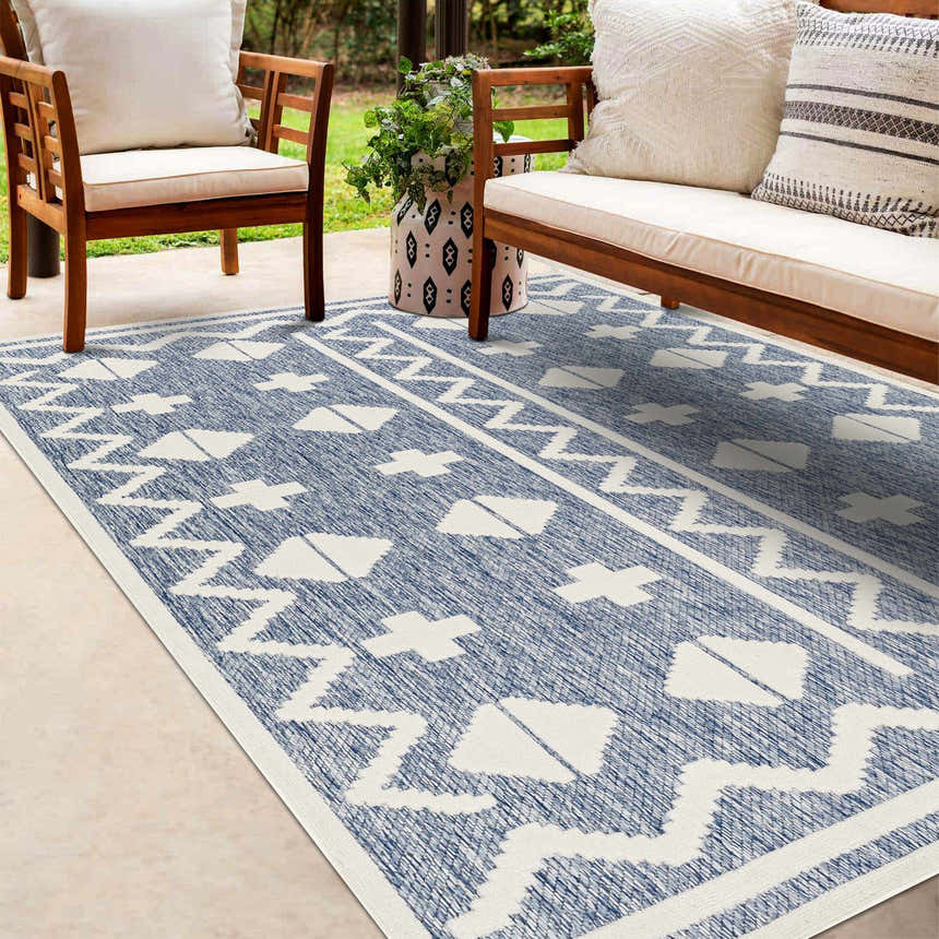 Patio scene with wooden chairs and Elio Blue Outdoor Rug featuring a geometric white pattern on a denim blue background. Roomscene-Rectangle