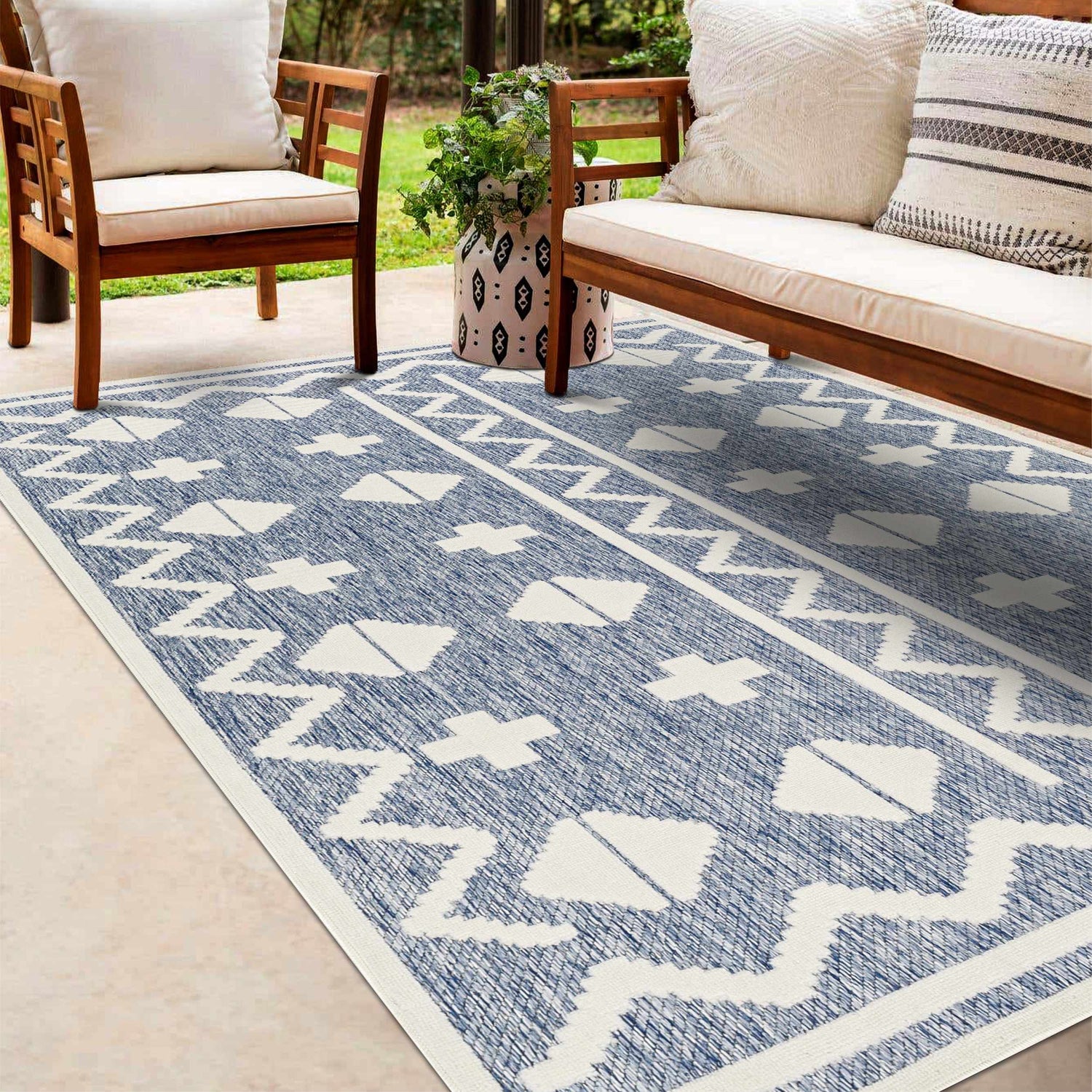 Patio scene with wooden chairs and Elio Blue Outdoor Rug featuring a geometric white pattern on a denim blue background. Roomscene-Rectangle