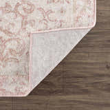 Close-up of the Snead Pink Floral Rug showing the light beige and pale pink floral design and the rug's backing. Fold