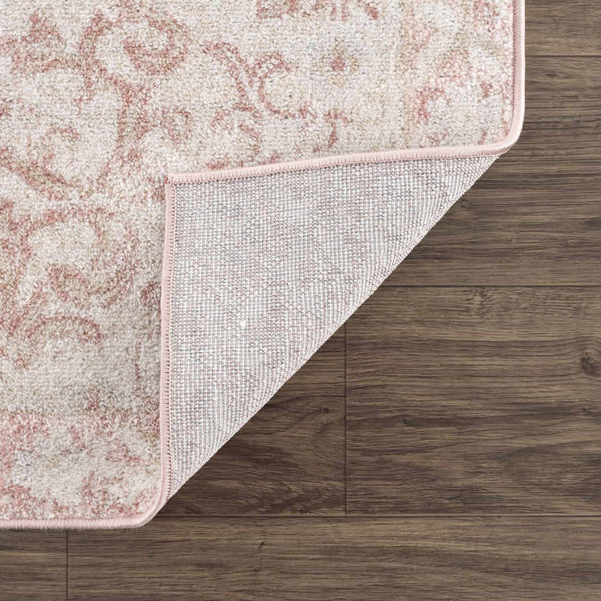Close-up of the Snead Pink Floral Rug showing the light beige and pale pink floral design and the rug's backing. Fold