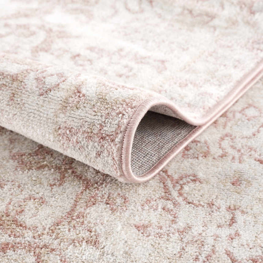 Close-up of the Snead Pink Floral Rug showing light beige and pale pink floral pattern and plush texture. Fold
