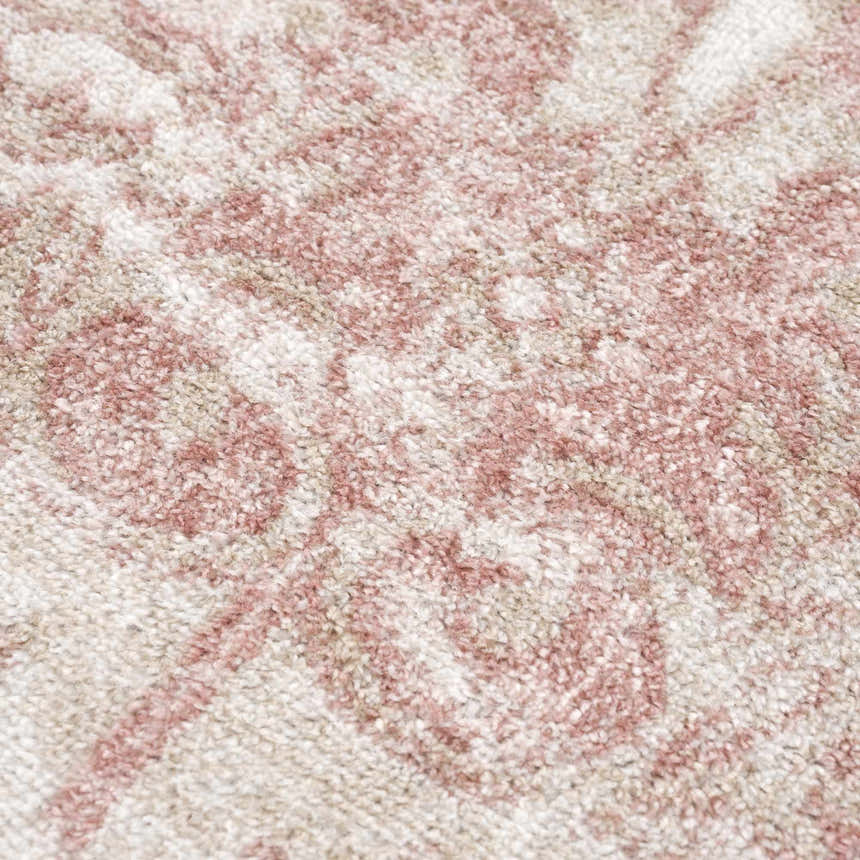 Close-up of the Snead Pink Floral Rug, showing its light beige base and pale pink floral pattern. Soft, textured weave. Texture