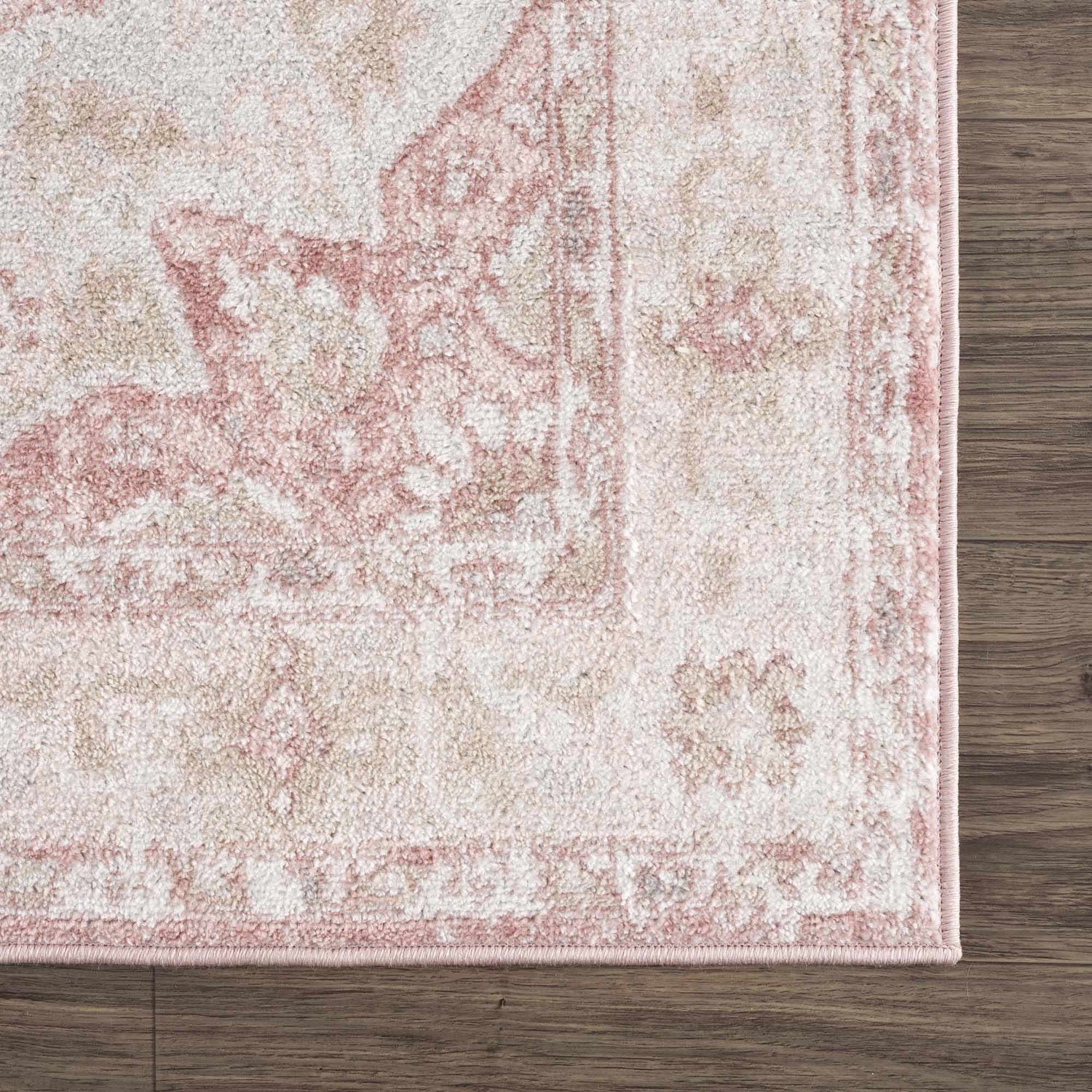 Close-up of the Kandos Blush & Light Pink Area Rug showing its cream, pale pink, and light beige traditional pattern. Corner