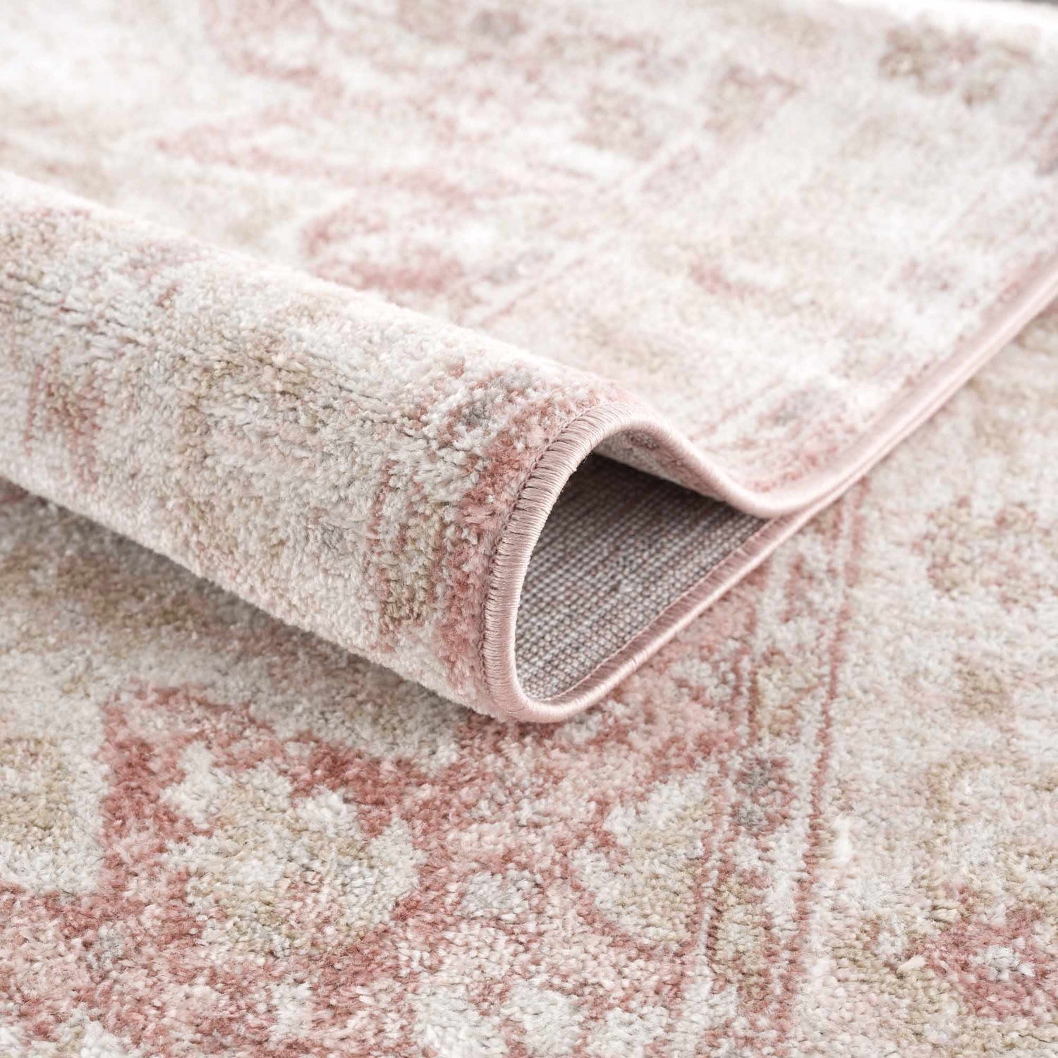 Close-up of the Kandos Blush & Light Pink Area Rug showing its plush texture and oriental-inspired pattern. Fold