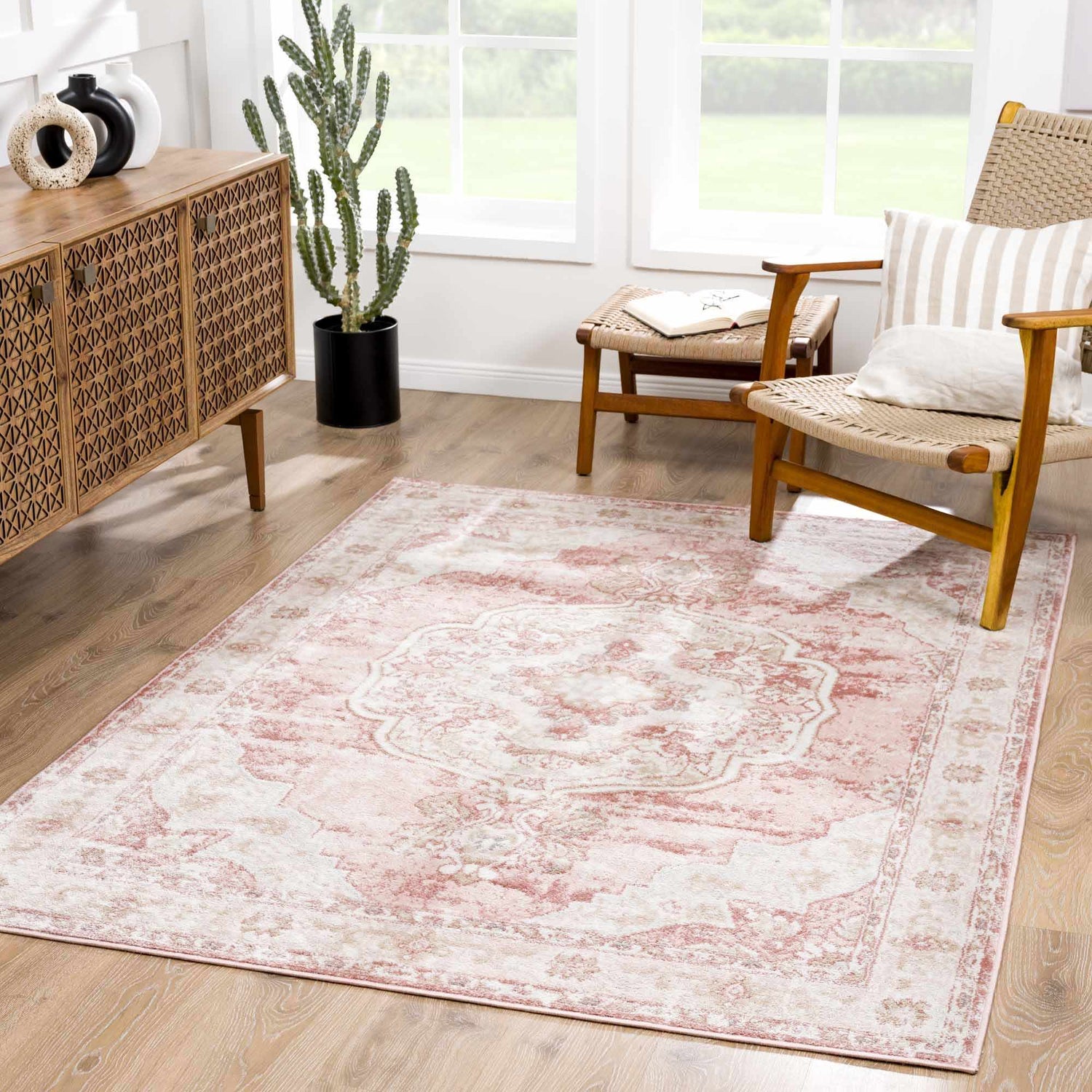 Living room scene with a Kandos Blush & Light Pink Area Rug, wood cabinet, woven chair, and natural light. Roomscene-Rectangle