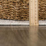 Close-up of Baqer Bone & Tan Textured Performance Rug showing pile height and texture next to a woven basket. Pile