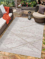Outdoor patio scene with Baqer Bone & Tan Textured Performance Rug, wicker furniture, stone flooring, and neutral decor. Roomscene-Rectangle