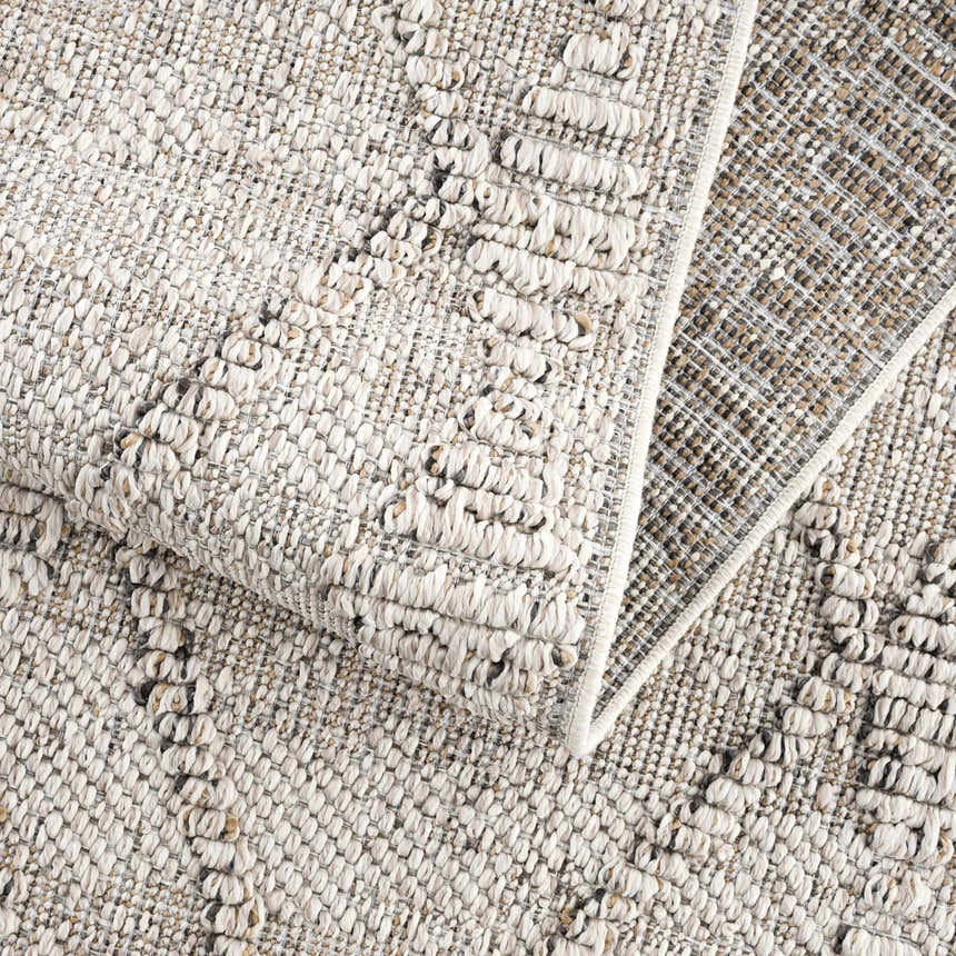 Close-up of the textured Nyla Bone Indoor & Outdoor Rug. Neutral bone color with a woven, raised pattern. Fold