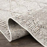 Close-up of Nyla Bone Indoor & Outdoor Rug. Neutral bone color, geometric pattern, textured weave, and durable polypropylene material. Fold
