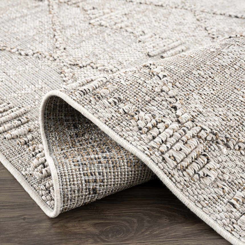 Close-up of Nyla Bone Indoor & Outdoor Rug. Neutral bone color, geometric pattern, textured weave, and durable polypropylene material. Fold
