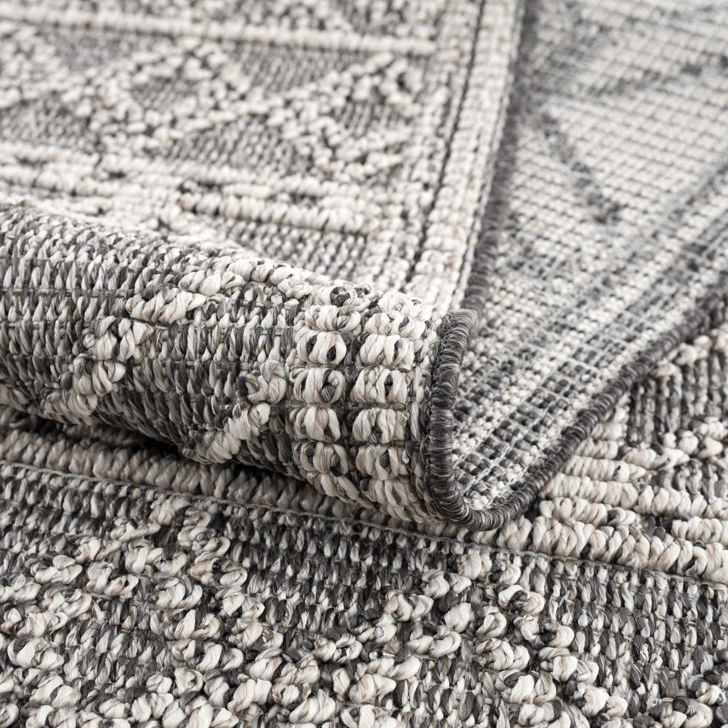 Close-up of the Diah Black & Bone Area Rug showing its textured weave, geometric pattern, and black and bone colors. Fold