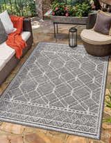 Outdoor patio scene with Diah Black & Bone Area Rug, wicker furniture, stone floor, and a cozy, inviting atmosphere. Roomscene-Rectangle