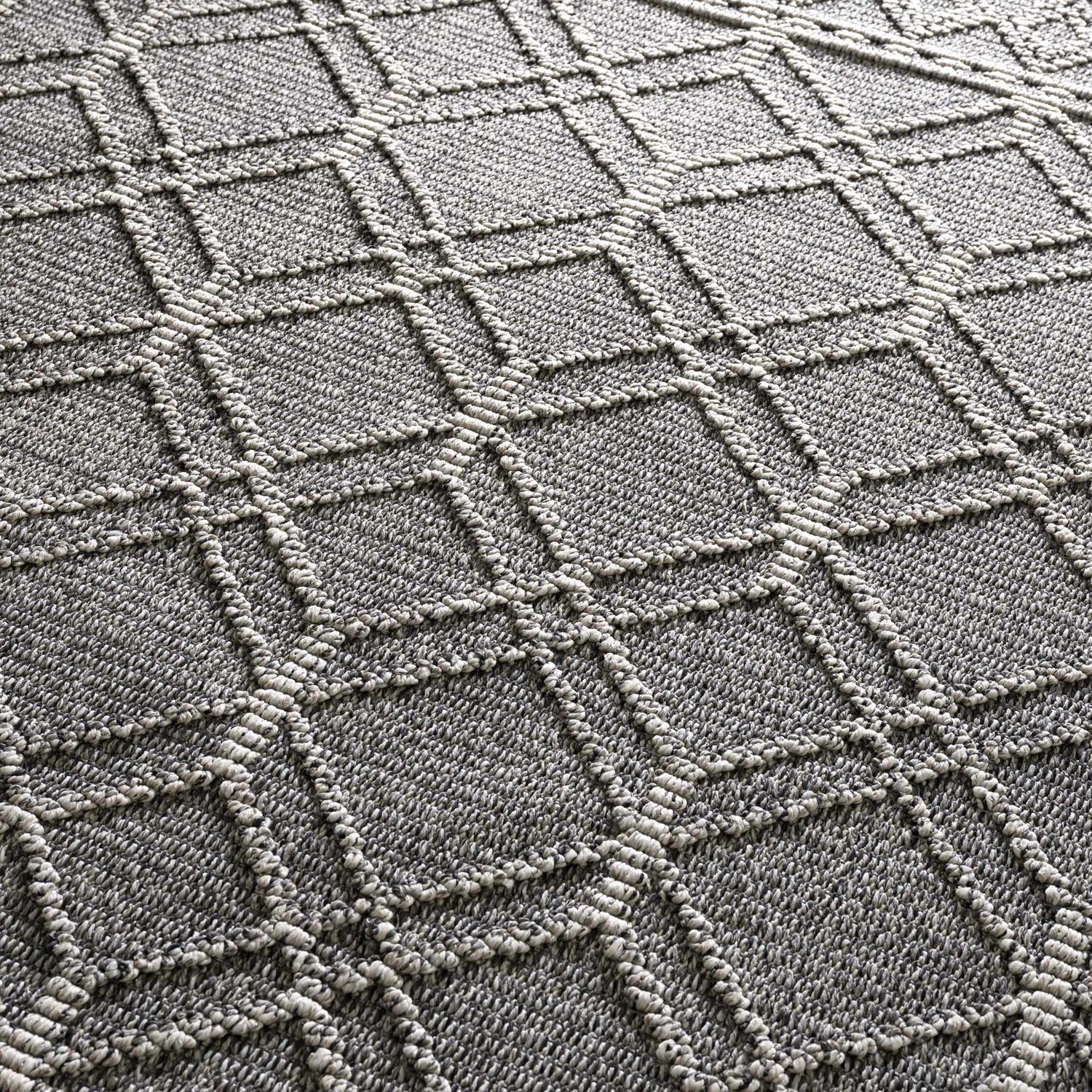 Close-up of the Diah Black & Bone Area Rug, showcasing its geometric diamond pattern and textured, machine-woven construction. Texture