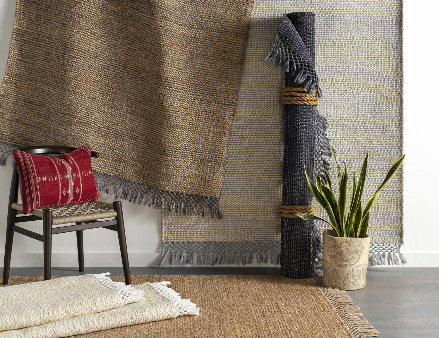 Partoun Area Rug in medium brown and tan, hand woven with jute and recycled PET yarn. Rug display with chair and plant. Styleshot
