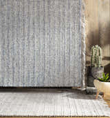 Contemporary living room scene with blue and cream Potterspury Area Rug, wood floor, and potted plants. Styleshot
