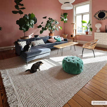 Living room with pink walls, blue sofa, and a Senneterre Bleached Jute Rug. Two cats are on the rug and sofa. Roomscene-Rectangle
